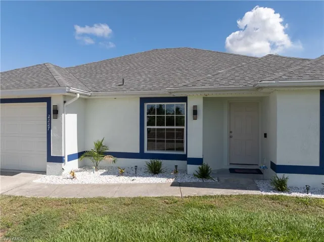 Ranch-style house with roof with shingles, an attached garage, and stucco siding