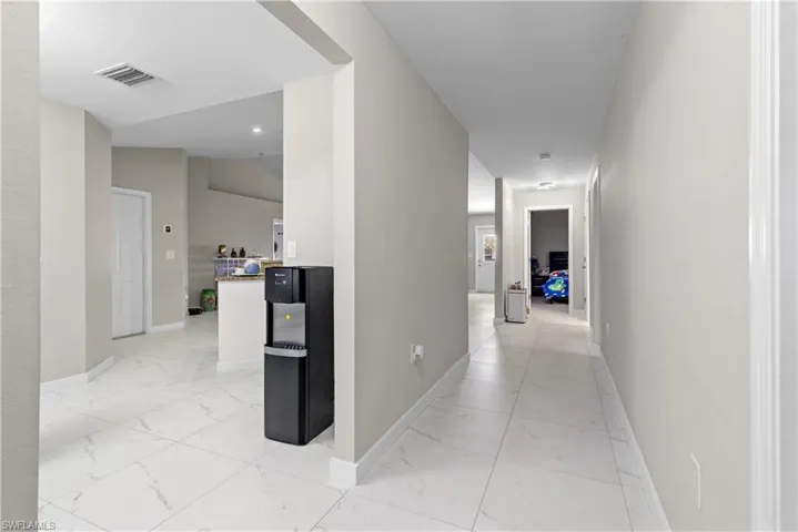 Corridor featuring light marble finish flooring and baseboards