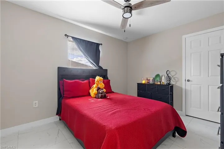 Bedroom with light marble finish floors, baseboards, and a ceiling fan