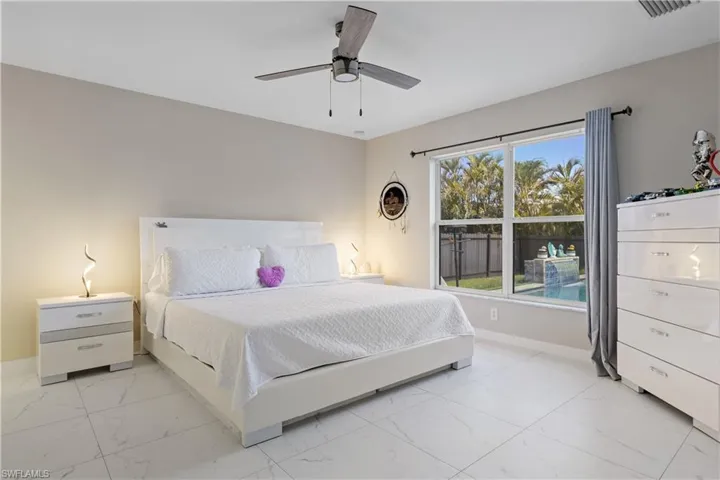 Bedroom featuring light marble finish floors, baseboards, and a ceiling fan