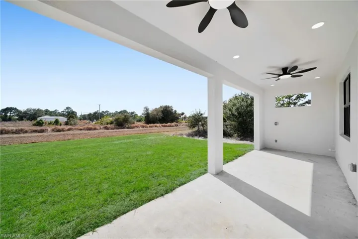 View of green lawn featuring ceiling fan and a patio area