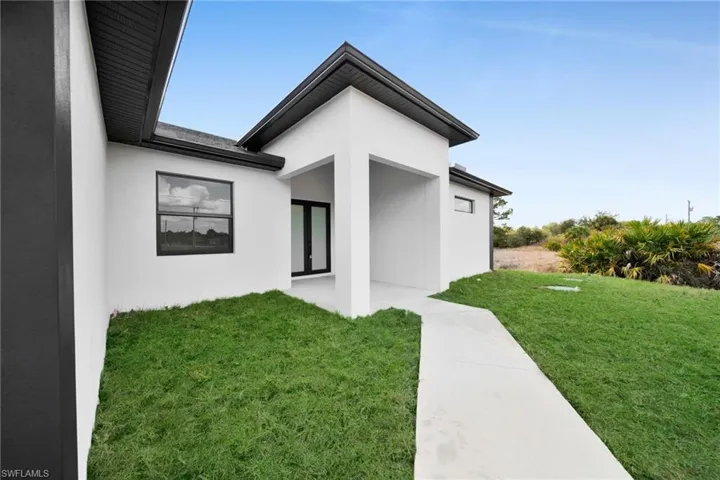 View of exterior entry featuring a yard, stucco siding, and french doors