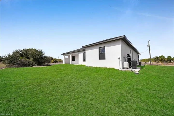 Rear view of property with a lawn and stucco siding