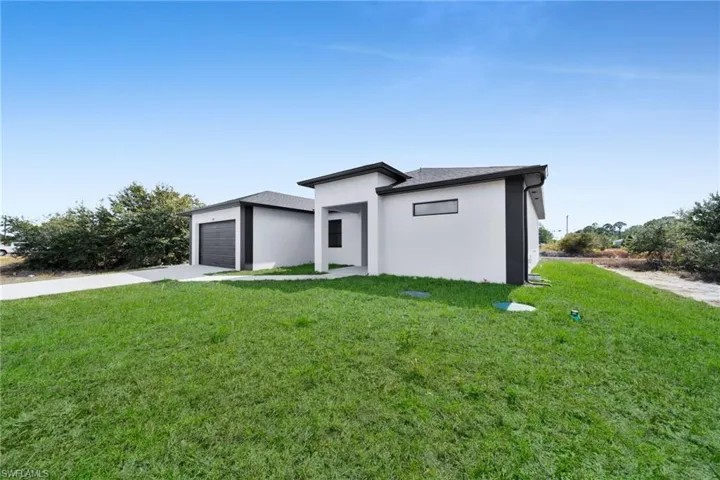 Prairie-style home with a front yard, driveway, an attached garage, and stucco siding