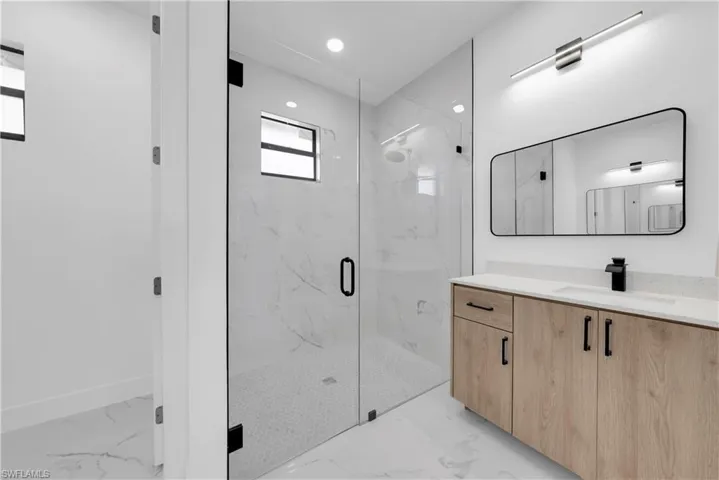 Full bathroom with vanity, a marble finish shower, recessed lighting, and light marble finish floors