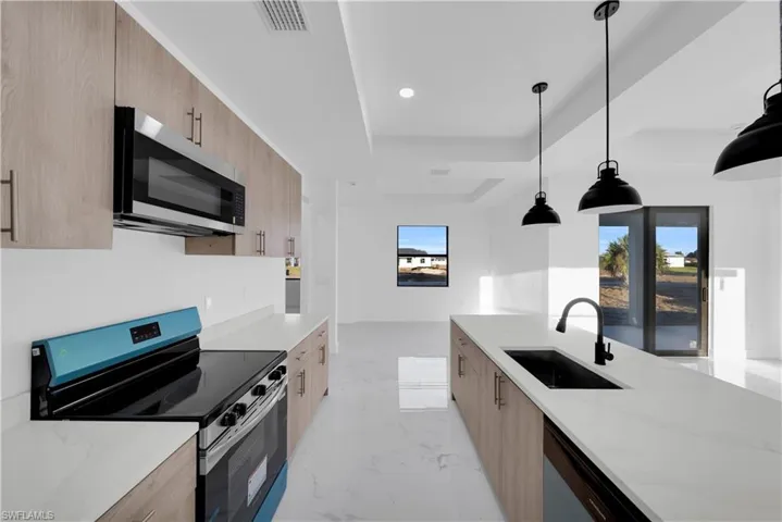 Kitchen featuring stainless steel appliances, light stone counters, modern cabinets, pendant lighting, and a tray ceiling