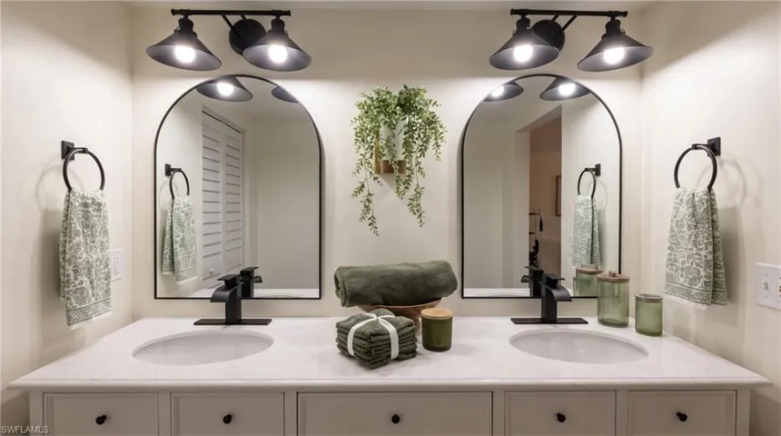 Dual vanity featuring individual vessel sinks, matte black faucets, arched mirrors, and coordinating overhead lighting