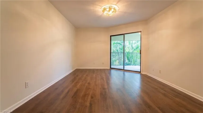Spacious room featuring wood-finish flooring, light-toned walls, and a ceiling-mounted light fixture