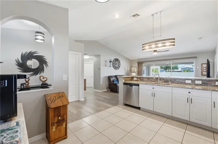 Open-concept kitchen with white cabinetry, granite countertops, and a stainless steel dishwasher
