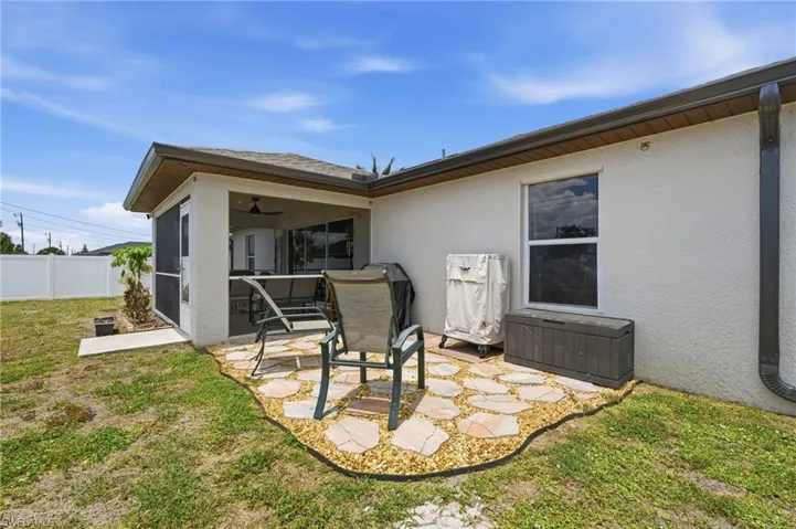 Screened patio with ceiling fan, featuring a stone paver patio area and an expansive grass yard