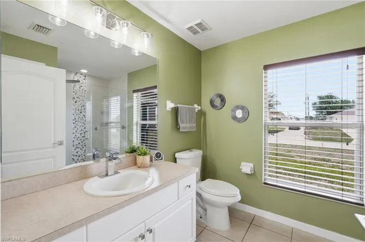 Full bathroom featuring a white vanity with an undermount sink, a large mirror, and a glass-enclosed shower with decorative tile