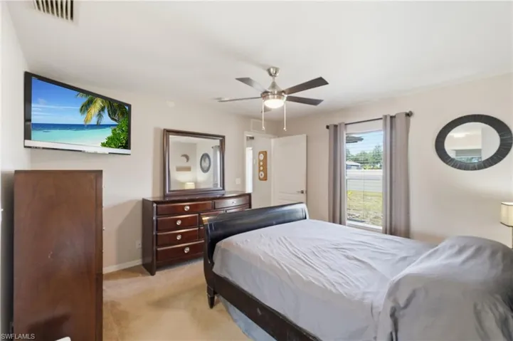 Interior room featuring carpet flooring, a ceiling fan with integrated lighting, and a window with curtain rods
