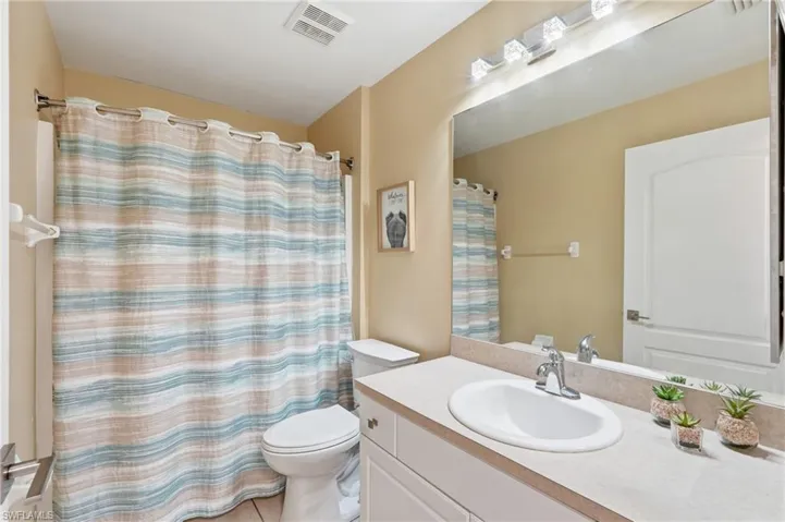 Bathroom featuring a single vanity with an integrated sink, polished chrome faucet, and spacious countertop