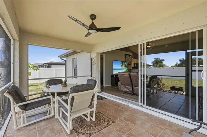 Screened patio featuring a ceiling fan, tile flooring with decorative inlay, and sliding glass door access to the interior