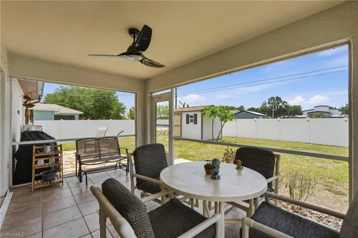 Screened patio featuring tile flooring, a ceiling fan, and a white privacy fence enclosing the backyard