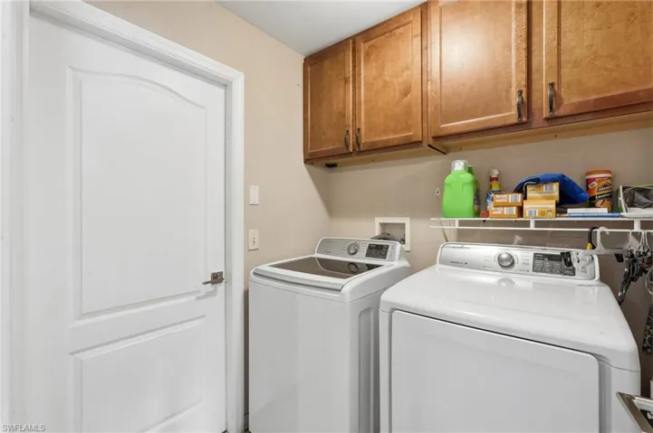 Dedicated utility area featuring overhead wood-finish cabinetry, a white wire shelf, and neutral wall paint