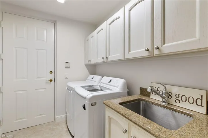 Laundry room with washer and clothes dryer, light tile patterned flooring, and cabinet space