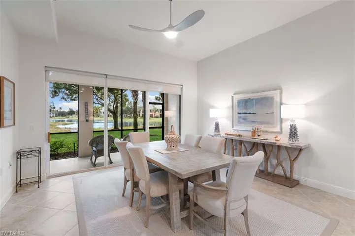 Dining area featuring a ceiling fan, light tile patterned floors, and a water view