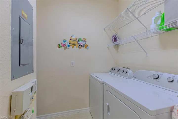 Laundry area with electric panel, washer and clothes dryer, and a textured wall