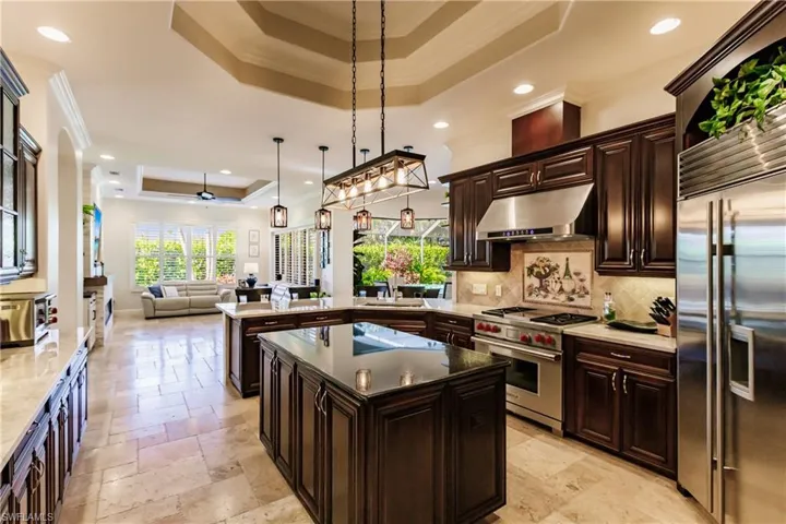 Kitchen featuring light tile floors, ceiling fan, a tray ceiling, and high end appliances