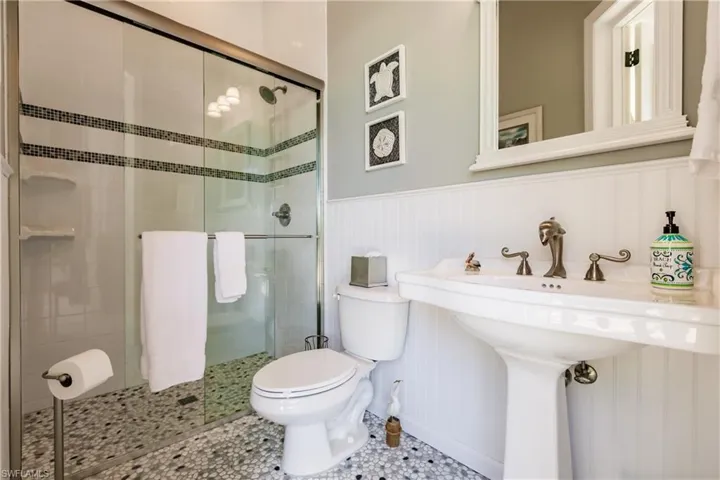 Bathroom with an enclosed shower, tile flooring, and toilet
