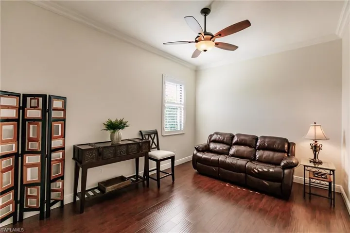 Living room with dark hardwood / wood-style floors, ceiling fan, and crown molding