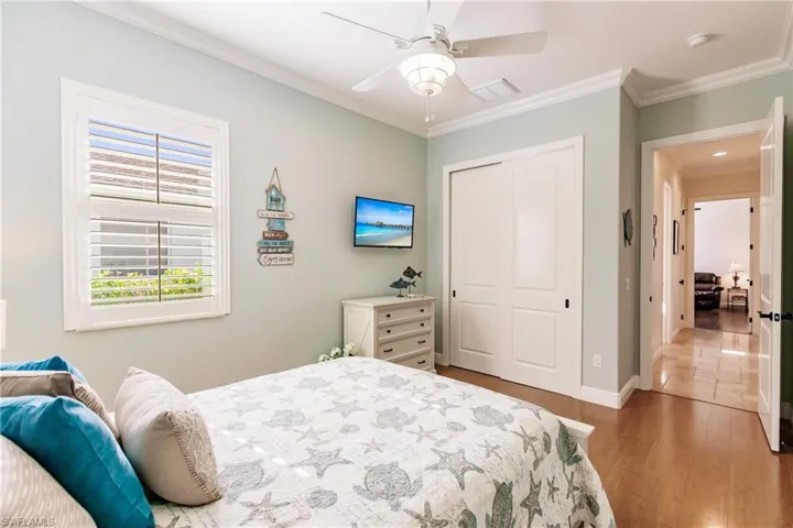 Bedroom featuring crown molding, ceiling fan, a closet, and hardwood / wood-style floors