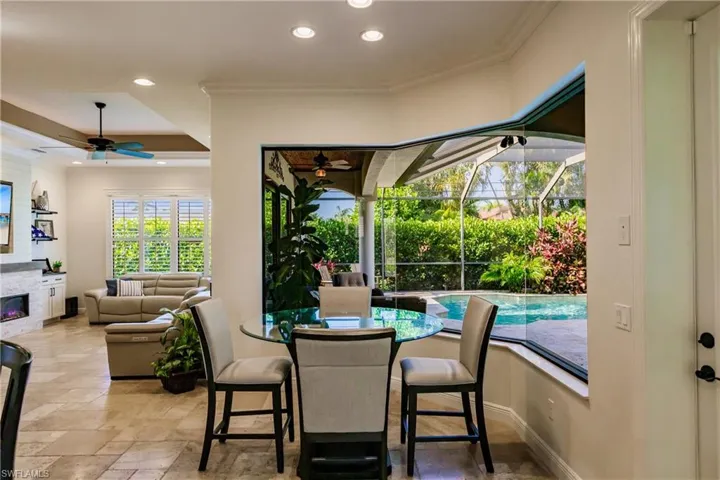 Tiled dining space with ceiling fan, a tray ceiling, and crown molding