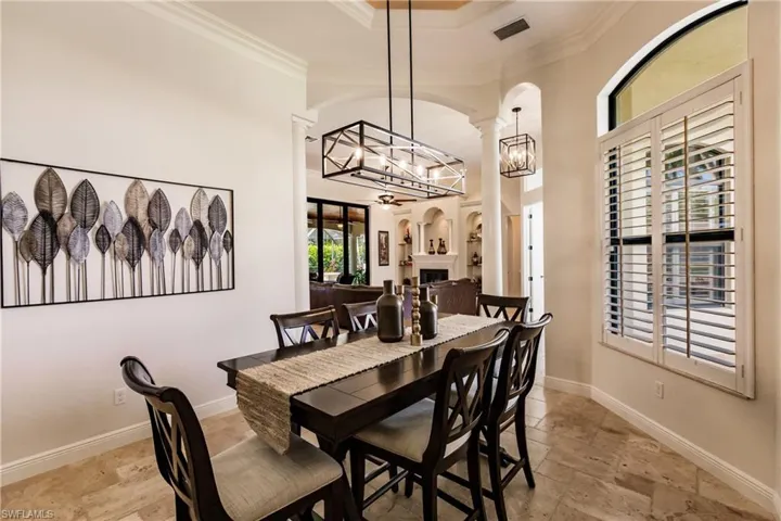 Tiled dining area with a chandelier, ornamental molding, and a raised ceiling