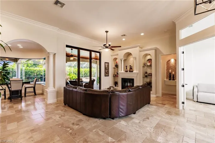 Living room featuring ceiling fan, light tile flooring, a wealth of natural light, and decorative columns