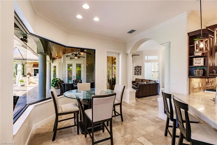 Dining space featuring ornate columns, ornamental molding, and light tile floors