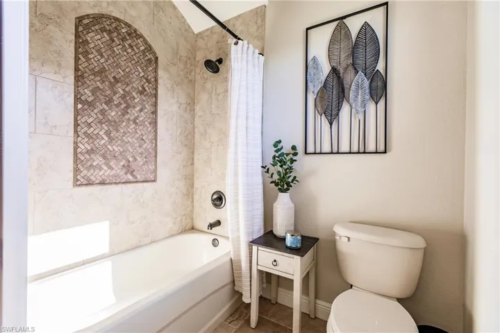 Bathroom featuring tile flooring, shower / bath combo, and toilet