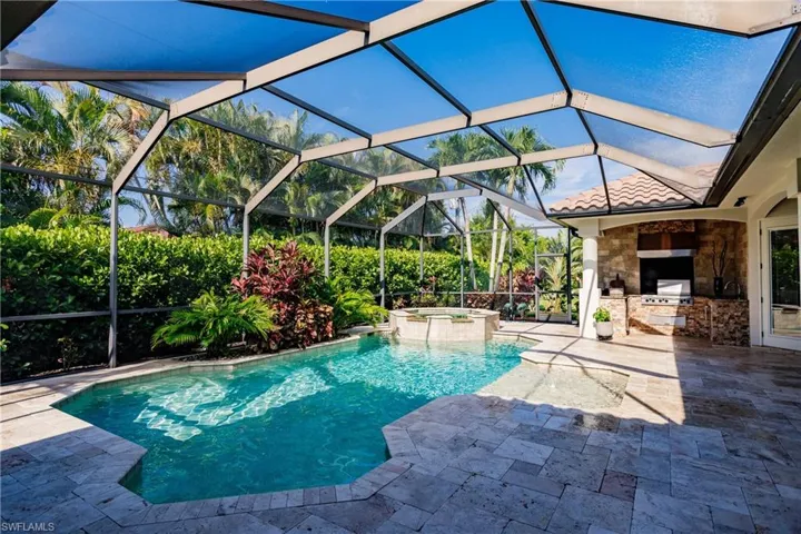 View of pool featuring an in ground hot tub, a patio, an outdoor kitchen, and a lanai