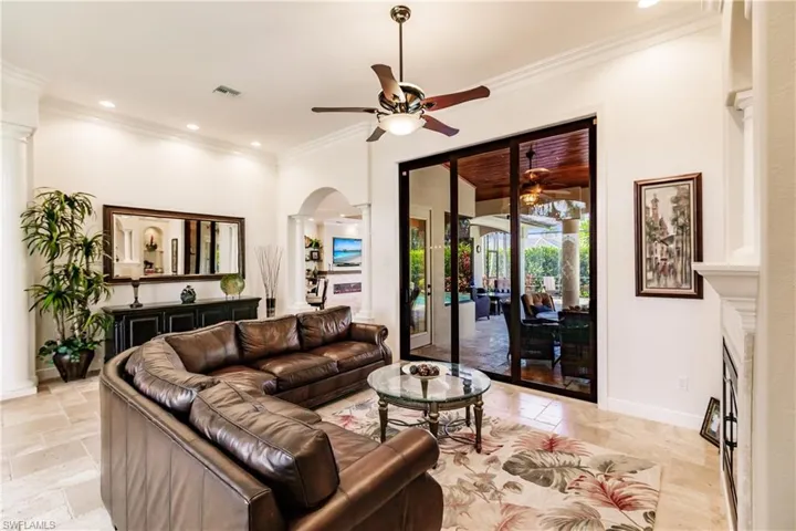Living room featuring decorative columns, ornamental molding, ceiling fan, and light tile floors
