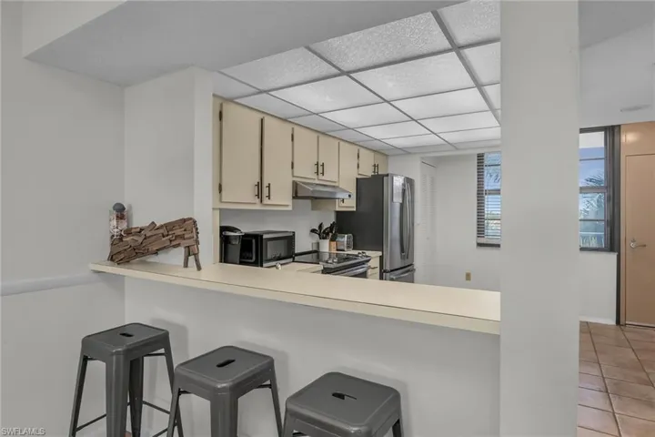 Kitchen featuring light countertops, appliances with stainless steel finishes, under cabinet range hood, cream cabinetry, and light tile patterned flooring