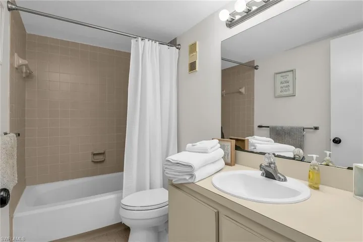 Full bath featuring shower / bath combo with shower curtain, vanity, visible vents, and toilet
