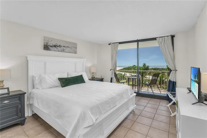 Bedroom featuring access to outside, light tile patterned flooring, and floor to ceiling windows