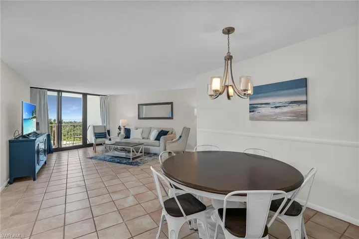 Dining room with light tile patterned floors, floor to ceiling windows, baseboards, and a notable chandelier