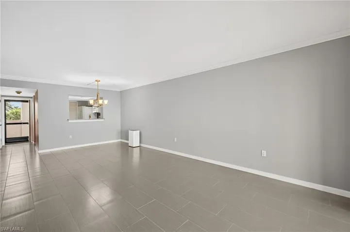 Empty room with crown molding and hanging lights