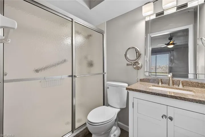Full bathroom with vanity, a stall shower, and ceiling fan