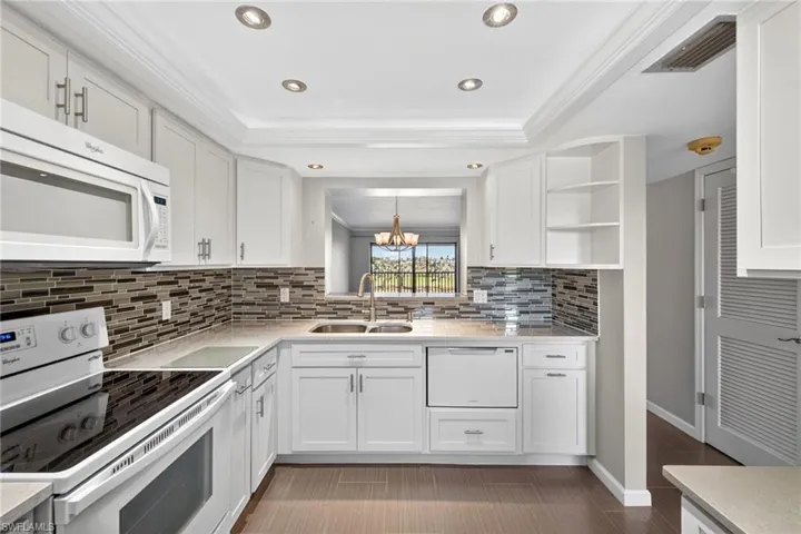 Kitchen featuring white appliances, open shelves, white cabinetry, light stone counters, and crown molding