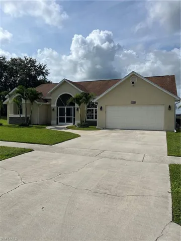 Single story home with stucco siding, a front yard, concrete driveway, a garage, and a shingled roof