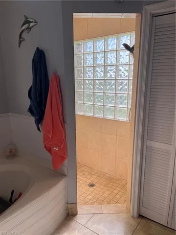 Full bathroom featuring a bath, a closet, tile patterned flooring, and a shower stall
