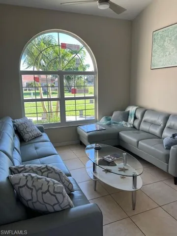 Living room featuring light tile patterned flooring, healthy amount of natural light, and ceiling fan