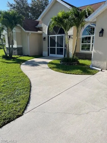 View of front facade with stucco siding, a front lawn, and driveway