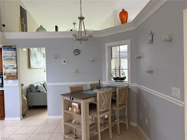 Dining room with light tile patterned flooring, a chandelier, and baseboards