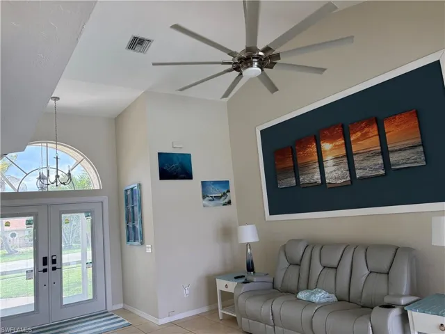 Living room with a ceiling fan, a chandelier, light tile patterned floors, and french doors