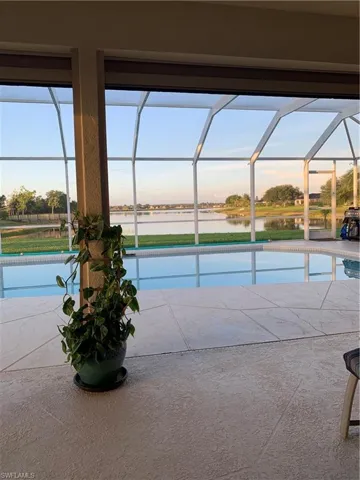 Swimming pool with glass enclosure, a patio area, and a water view