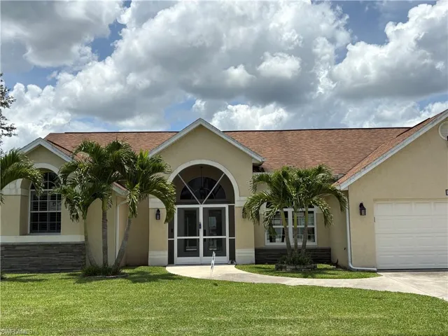 View of front of home with stucco siding, a front yard, a shingled roof, an attached garage, and driveway