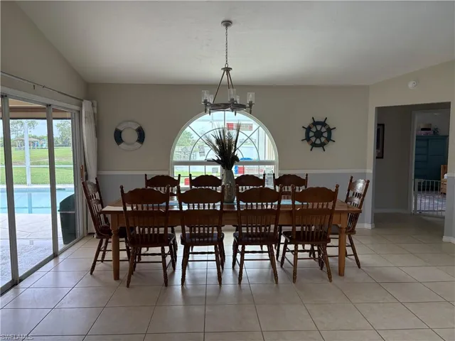 Dining room with a chandelier, vaulted ceiling, healthy amount of natural light, and light tile patterned floors